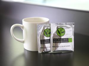 due sacchetti di astingasting accanto a una tazza di caffè bianco di APA Hotel Toyama Ekimae a Toyama