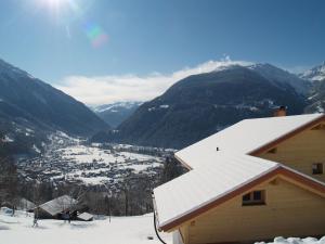 un techo cubierto de nieve de un edificio con montañas en el fondo en Haus grüner Wald, en Bartholomäberg