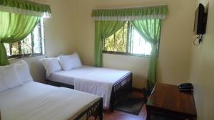 a room with two beds and a table and two windows at Bright Star Hotel in Arusha