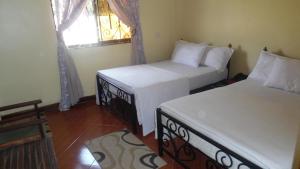 two beds in a room with a window at Bright Star Hotel in Arusha