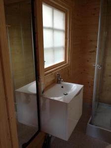 La salle de bains est pourvue d'un lavabo blanc et d'une fenêtre. dans l'établissement Hjemstavnsgårdens Camping & Cottages, à Glamsbjerg