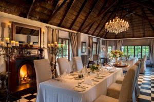 una sala da pranzo con tavoli, sedie e lampadario a braccio di Hunter's Country House a Plettenberg Bay