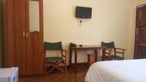 a bedroom with a table and chairs and a tv at Bright Star Hotel in Arusha