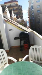 een balkon met een groene tafel en witte stoelen bij Apartamento Década Cervantes 19 in Fuengirola