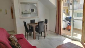 een woonkamer met een tafel en stoelen en een rode bank bij Apartamento Década Cervantes 19 in Fuengirola