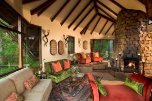 a living room with a stone fireplace and a couch at Tsala Treetop Lodge in Plettenberg Bay +54 photos