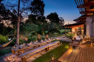 une terrasse en bois avec une longue table dans un jardin dans l'établissement Tsala Treetop Lodge, à Plettenberg Bay