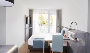 1 dormitorio con cama, escritorio y ventana en Living Hotel Nürnberg en Núremberg