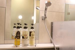 a bathroom with four bottles of alcohol on a shelf at Cabin & Capsule Hotel J-SHIP Osaka Namba in Osaka