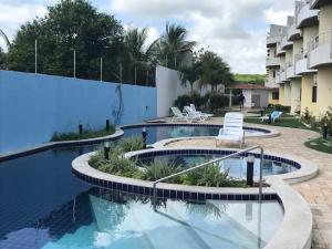 a swimming pool with chairs and a building at Ocean View Tabatinga in Nísia Floresta