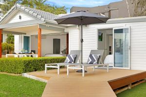 eine Terrasse mit 2 Stühlen und einem Sonnenschirm in der Unterkunft The Beach House North Wollongong in Wollongong