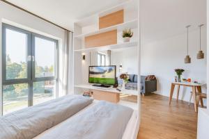 a white bedroom with a bed and a tv at SMARTments business Berlin Karlshorst in Berlin