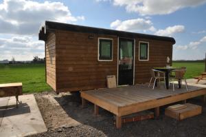 une petite maison avec une terrasse en bois et une table dans l'établissement Your nice waggon at the Cow's Paradise, à Amsterdam