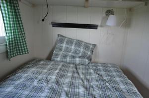 a bed in a small room with a plaid pillow at Your nice waggon at the Cow's Paradise in Amsterdam