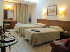 a hotel room with three beds and a table at Hotel Solomou Athens in Athens