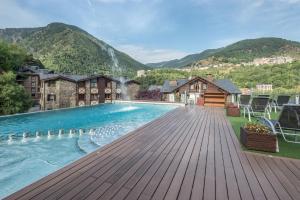 una piscina en una terraza con montañas al fondo en Aparthotel AnyosPark Mountain & Wellness Resort, en Anyós