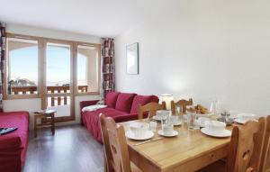 a living room with a table and a red couch at Résidence Odalys La Licorne in La Plagne