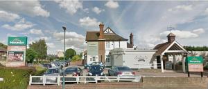 a parking lot with cars parked in front of a building at 118 Shepherds Lane in Dartford