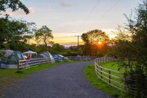 una strada sterrata con tende e una recinzione al tramonto di Loughcrew Glamping a Oldcastle