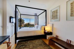 Bom Sucesso Resort في فاو: غرفة نوم بسرير كبير ونافذة كبيرة