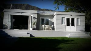 a small white house with a table and chairs at Corban Cottage in Hermanus