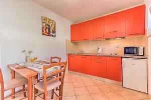 a kitchen with red cabinets and a table with chairs at Apartments Katarina in Bol