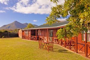 a cabin with chairs and a table in front of it at Horizon Cottages in Noordhoek
