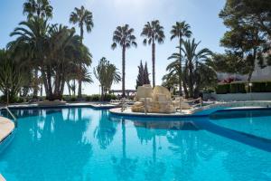 a large swimming pool with chairs and palm trees at Apartamentos Paraíso Mar in Calpe