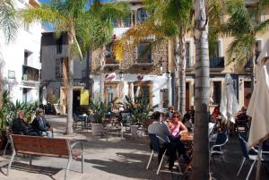 un gruppo di persone sedute ai tavoli in un cortile con palme di Apartamento Net by Family Homes a Denia