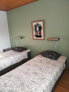 a room with two beds and a picture on the wall at Hotelli Puustelli Lieksa in Lieksa