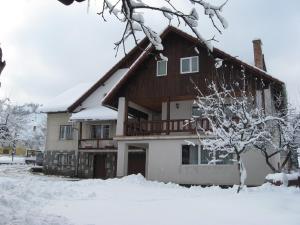 een huis met sneeuw op de grond ervoor bij Pensiunea Luminita in Bran