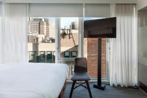 a bedroom with a bed and a television and a window at Arlo NoMad in New York