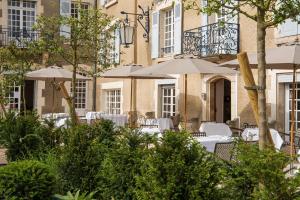 a patio with tables and umbrellas in front of a building at Hôtel Restaurant De La Poste & Du Lion D'or in Vézelay