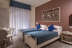 a bedroom with a bed with blue and white sheets at Hotel Corallo in Albinia