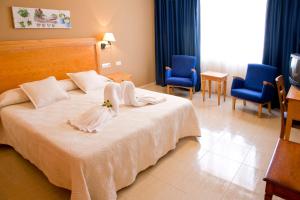 1 dormitorio con 1 cama con sábanas blancas y sillas azules en Aparthotel Bahia Pinosol en Jávea