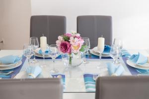 a table with glasses and a vase of flowers on it at Maiv Apartments in Rogoznica