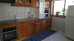 cocina con armarios de madera, fregadero y nevera en Apartamento T3 Amorosa, en Viana do Castelo