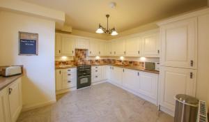 a large white kitchen with white cabinets and appliances at Westfield Country Barns in Braunston