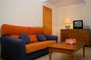 an orange couch in a living room with a table at Aparthotel Bahia Pinosol in Jávea