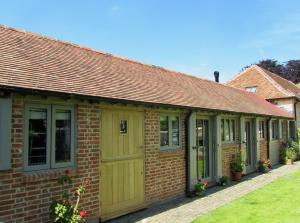 a brick house with yellow doors and windows at Bury Knowle Stables in Oxford