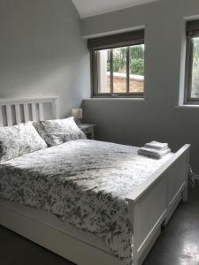 a bedroom with a white bed with a floral bedspread at Bury Knowle Stables in Oxford