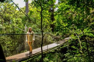 uma mulher de pé numa ponte suspensa na floresta em Jaguarundi Lodge - Monteverde em Monteverde