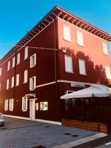 un edificio rosso con un ombrello davanti di Venice Apartments Dante a Mestre
