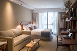 Habitación de hotel con cama y sofá en AQ Tailored Suites en Buenos Aires