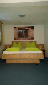 ein Schlafzimmer mit einem Holzbett mit grünen Kissen in der Unterkunft Haus Bilgeri in Nesselwängle