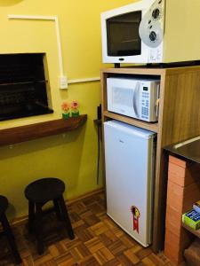 cocina con nevera, microondas y taburete en Casa Santos Dumont, en Gramado