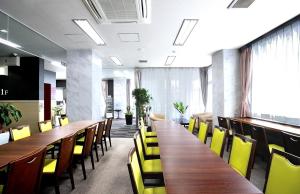a conference room with wooden tables and yellow chairs at Sunstay Kaseda in Kaseda