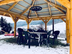 a table and chairs under a pavilion in the snow at Malinowy Domek in Młyńczyska