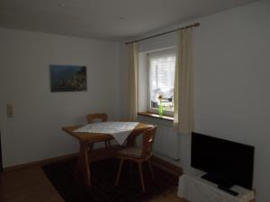 Habitación con mesa, TV y ventana. en Angelas Apartment en Grenzach-Wyhlen