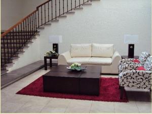 een woonkamer met een witte bank en een rood tapijt bij Hotel Gobernador in Durango